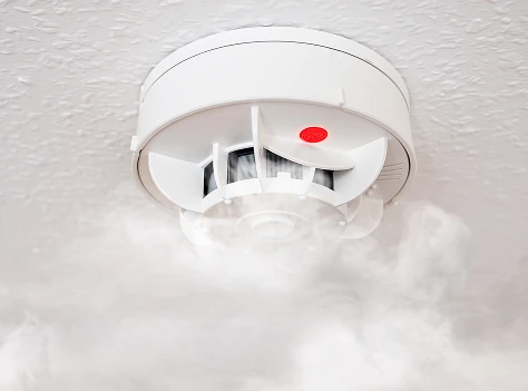 Ceiling-mounted smoke detector detecting smoke during a fire alarm event
