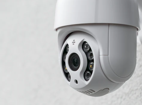 White dome security surveillance camera mounted on a wall for building monitoring